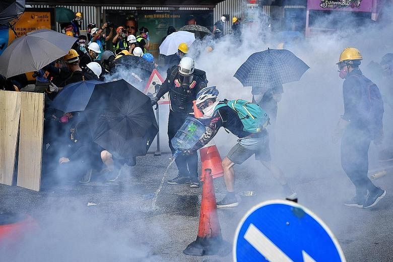Above: Demonstrators gathering to block the Cross Harbour Tunnel in Hong Kong's Hung Hom district yesterday. Key roads were blocked, cutting major arteries linking Hong Kong Island and the Kowloon peninsula. PHOTO: BLOOMBERG Right: Protesters rushing