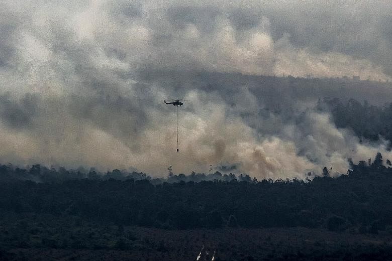 A helicopter carrying water attempting to extinguish a fire raging at a peatland forest in Pelalawan district, Riau province, last Friday. More than 5,000 personnel, including reinforcements from the military and police, have been deployed to Riau to