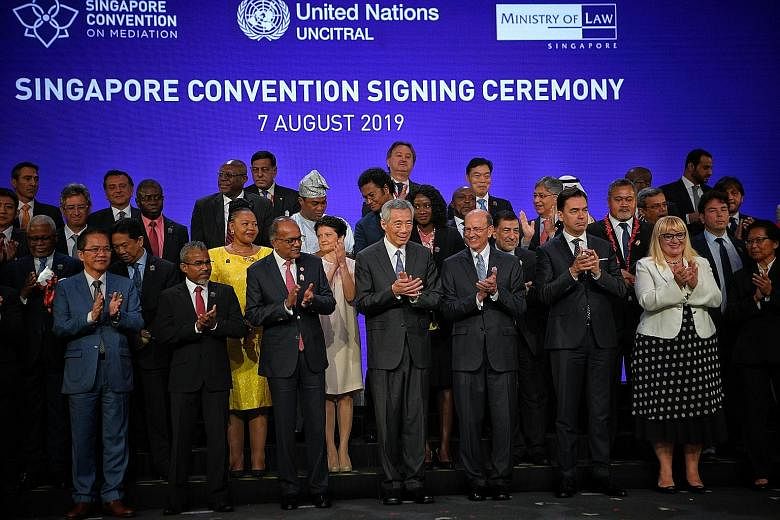Prime Minister Lee Hsien Loong, flanked by Law and Home Affairs Minister K. Shanmugam and UN Assistant Secretary-General for Legal Affairs Stephen Mathias, with signatories and heads of delegations after the signing of the Singapore Convention on Med