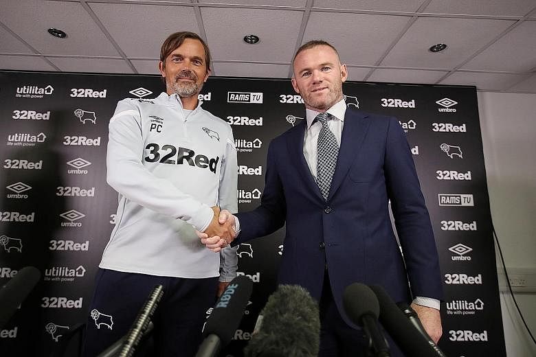 Derby County manager Phillip Cocu (far left) and his prized recruit Wayne Rooney pose during the press conference to unveil the former England and Manchester United star on Tuesday. PHOTO: REUTERS
