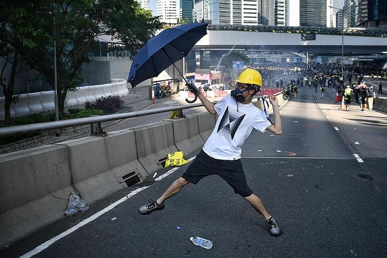 A protester, armed with an umbrella as a shield, throwing an egg at the police outside the Legislative Council in Hong Kong on Monday. More protests are planned in several districts across the city this weekend.