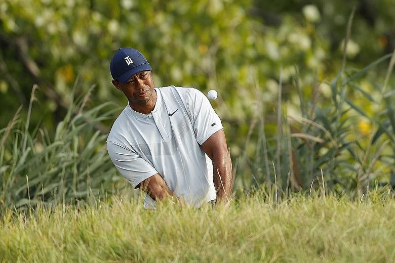 Tiger Woods playing a shot on the 14th hole during Thursday's first round of The Northern Trust at Liberty National Golf Club. He shot a four-over 75 and was near last. PHOTO: AGENCE FRANCE-PRESSE