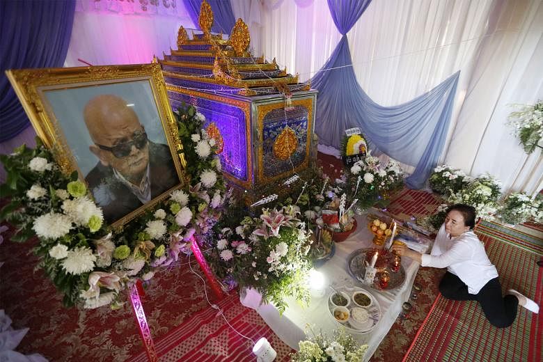 Nuon Chea's relative lighting incense in front of his coffin at a temple in Cambodia's western Pailin province on Thursday. The Khmer Rouge leader, who died on Sunday in a Phnom Penh hospital at age 93, was cremated yesterday.