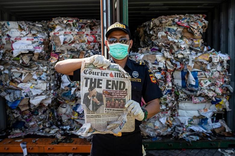 An Indonesian customs officer holding up a newspaper originating from Australia at a port in Surabaya on July 9. The container from which it was retrieved should have contained only waste paper, but the authorities also found hazardous materials and 