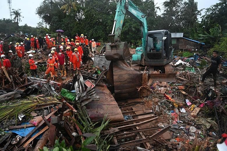 An excavator removing damaged structures yesterday after a landslide in Paung, Mon state.