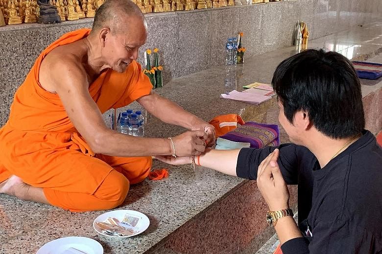 (Above) A traditional Baci ceremony at Wat Phabath in the Bolikhamxay Province, where a monk ties a piece of string on a person's wrist as a blessing.(Right) The Sikhottabong Stupa in Thakhek is a revered sacred site with an impressive 29m-tall golde
