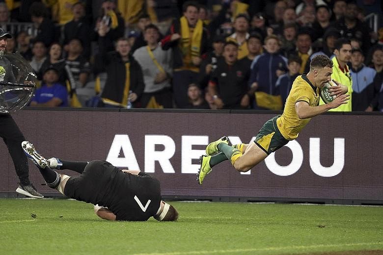 Australia's Nic White evading All Black Sam Cane's last-ditch tackle to score a try during their Bledisloe Cup match in Perth yesterday. The home side won 47-26, their first win over the world champions since 2017. PHOTO: ASSOCIATED PRESS