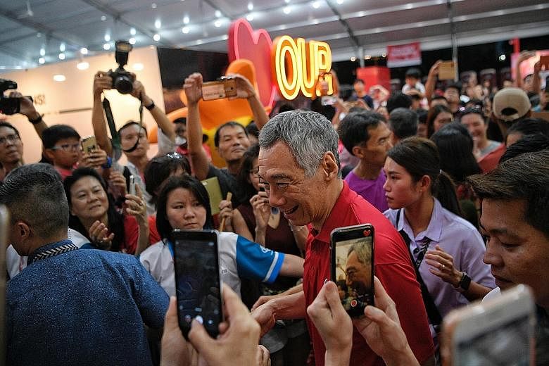 Above: Prime Minister Lee Hsien Loong mingling with the crowd during the National Day heartland celebration in Bishan yesterday.Right: Mr Lee, as a student in Catholic High School, leading the combined reed and brass band in the National Day Parade.