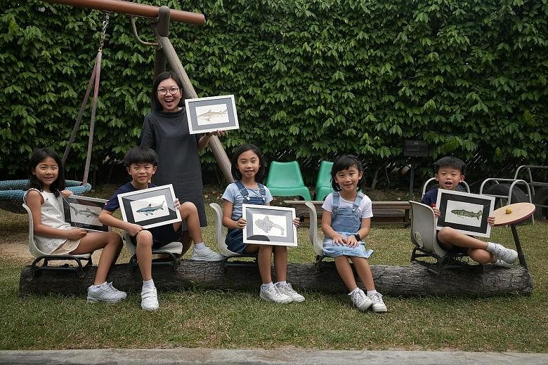 EtonHouse Pre-School senior teacher Wong Wei Sum with the children - (from left) Lily Huang, Liam Ong, Chloe Tan, Katie Tan and Lucius Ong - behind a video that was part of WWF-Singapore's anti-shark fin campaign on social media last year. 