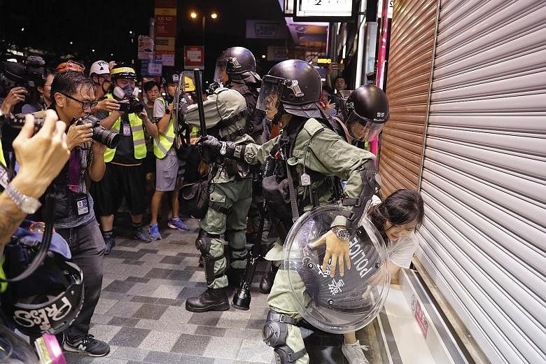 Police detaining a teenage girl during a confrontation with protesters in Hong Kong yesterday. More protests are expected today.