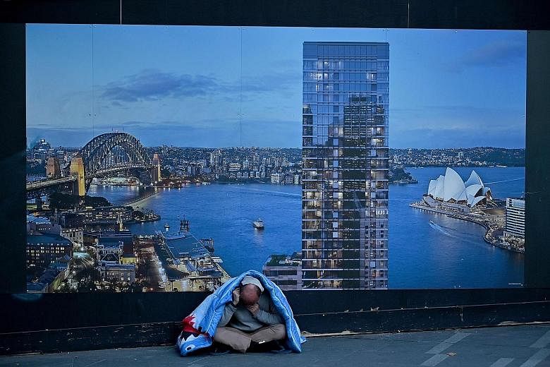 A homeless man in front of a construction site hoarding in Sydney. There has been a severe slump in building activity in the past year.