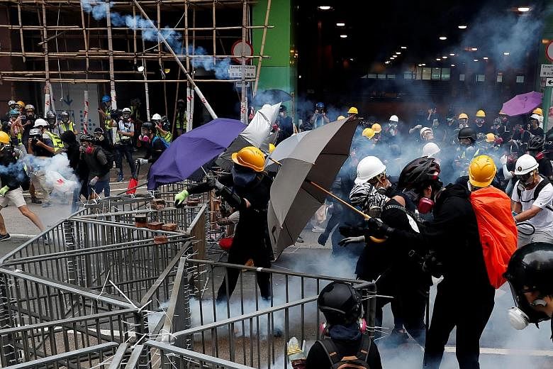 Protesters responding to tear gas fired by police during a rally in Hong Kong's Sham Shui Po area yesterday. Tear gas was even used indoors, at a train station in Kwai Fong, though it is rare for police to do so. Beijing says criminals and agitators 