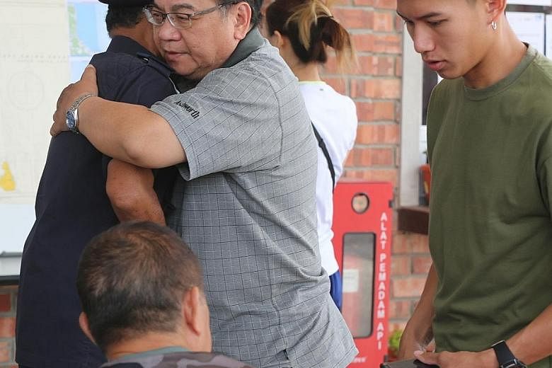 Mr Peng Mun Kit, the husband of missing kayaker Puah Geok Tin, receiving a hug from Johor Malaysian Maritime Enforcement Agency director Aminuddin Abdul Rashid yesterday in Mersing, Johor. Beside them is the couple's son Louis. Above: Madam Puah Geok