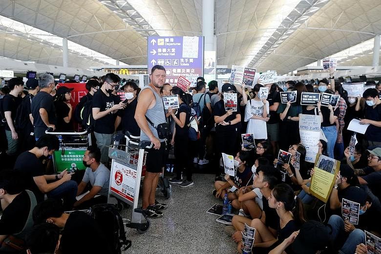 Above: Travellers gathering at the closed check-in counters as they waited for updates. Left: Protesters walking on a highway near the airport as public transport options, including the express train into the city, bus station and taxi stands, were i