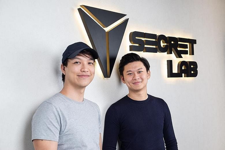 Secretlab's gaming chairs range from synthetic leather options for $429 to full leather designs for about $1,000. Secretlab founders Alaric Choo (wearing cap) and Ian Alexander Ang started the company in 2014, and its gaming chairs are now available 