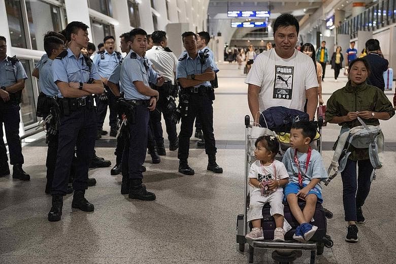 Police protecting passengers at the Hong Kong airport on Wednesday as flights resumed. Sentiment on the ground appears to be turning in favour of the government. PHOTO: DPA