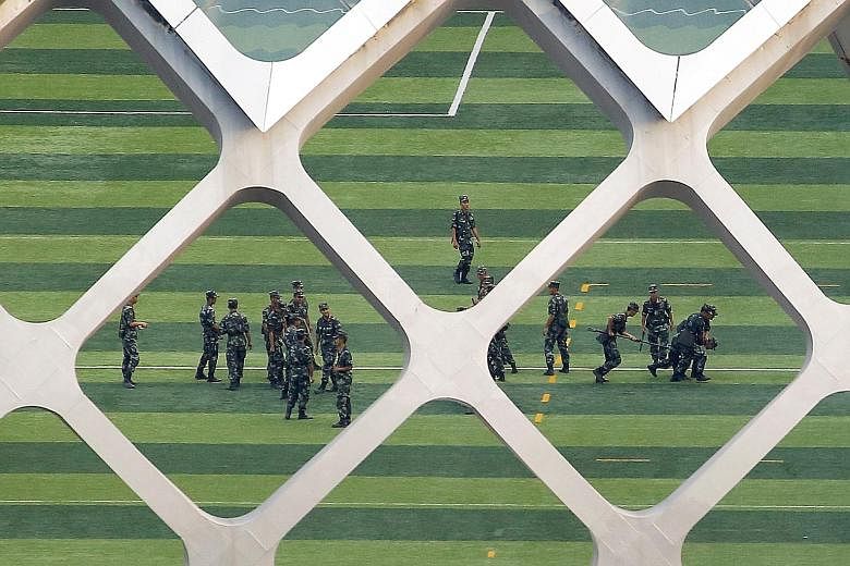 Chinese armed police (above) practising their tactics yesterday at the Shenzhen Bay Sports Centre in Shenzhen, just across the border from Hong Kong, while trucks and armoured personnel carriers (right) were seen parked outside.