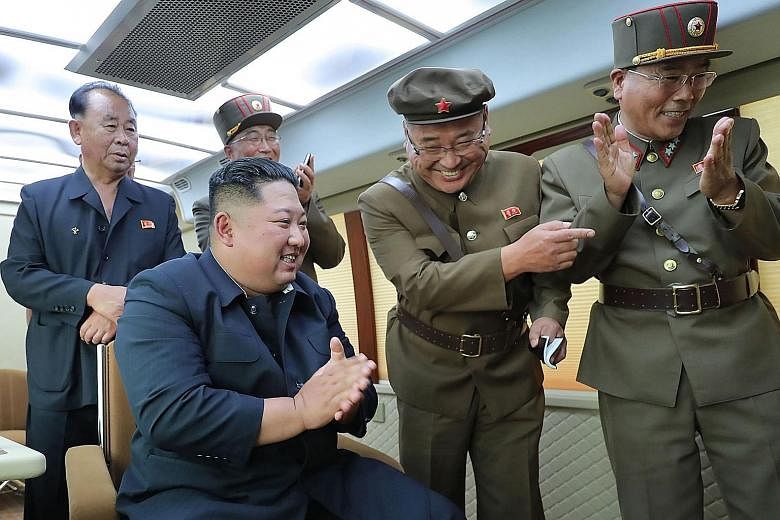 North Korean leader Kim Jong Un (seated) celebrating the successful test-firing of a new weapon at an undisclosed location on Friday.