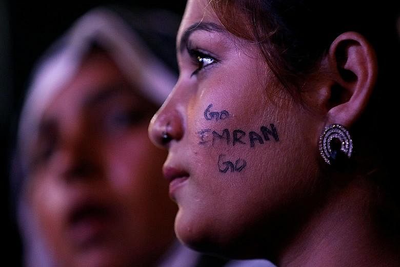 Left: A supporter of an opposition party listening to a speech during a countrywide protest last month called "Black Day" against the government of Prime Minister Imran Khan (above). PHOTOS: REUTERS, AGENCE FRANCE-PRESSE
