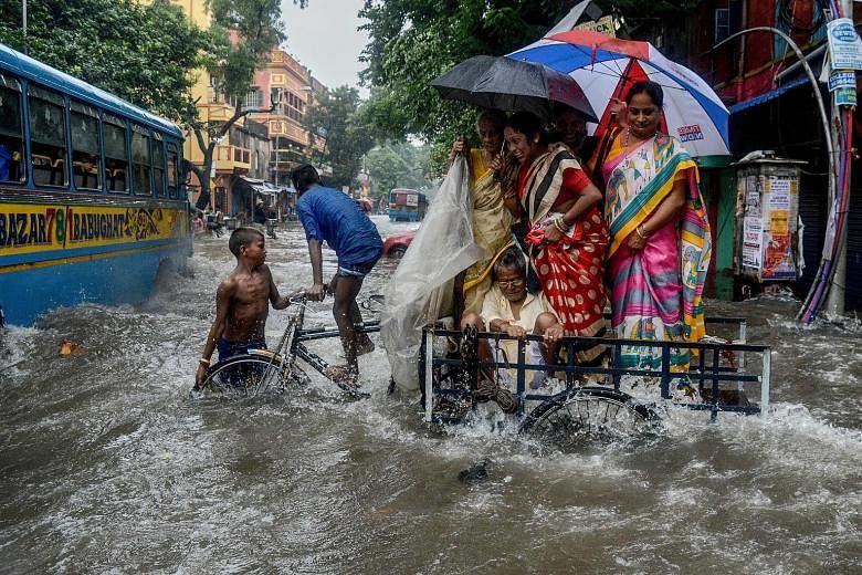 A family crossing a flooded road amid gushing water following heavy rain in Kolkata. Flood warnings were sounded in parts of northern India yesterday as the nationwide death toll in monsoon rains surpassed 1,000. India's monsoon season from June to S