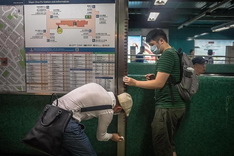 Activists cleaning an information board at Sham Shui Po MTR station in Hong Kong yesterday. Last week, police used tear gas to disperse protesters near the station. Weeks of protests have plunged Hong Kong into a crisis. PHOTO: EPA-EFE Protesters at 