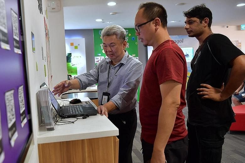 Service ambassador Ng Thiam Hock (left), 60, guides customers through electronic transactions and attends to their inquiries at the HDB Punggol branch office. Having upskilled to take on different roles, he is among the first batch of public officers