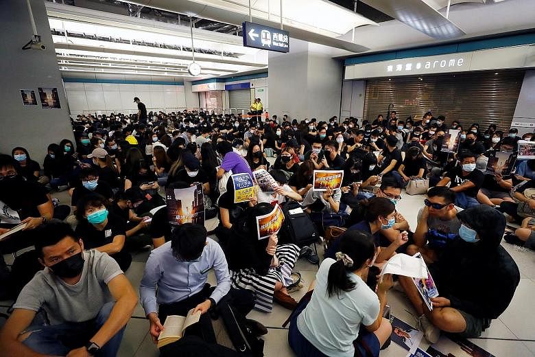 Left: A silent sit-in protest yesterday at Hong Kong's Yuen Long MTR station, which was the scene of an attack on protesters by suspected triad gang members a month ago. The attack left nearly 50 people in hospital, including passers-by. PHOTOS: REUT