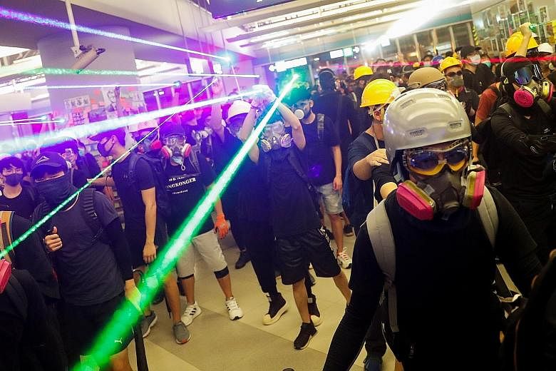 Protesters facing off with riot police inside the Yuen Long station yesterday. Some put on hard hats and gas masks, while others sprayed fire extinguishers and poured detergent, beer and oil on the concourse to impede entry by the police.