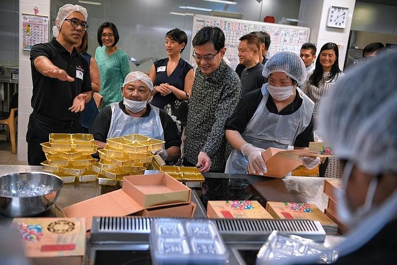 Deputy Prime Minister Heng Swee Keat speaking to Samsui Kitchen staff and volunteers at the Enabling Village in Lengkok Bahru yesterday. They were preparing mooncake boxes before the National Volunteer and Philanthropy Centre Company of Good Fellowsh