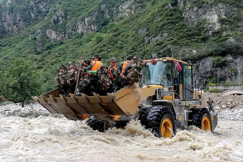 A bulldozer transporting Chinese paramilitary police officers as they headed on Thursday to the site of a mudslide caused by heavy rainfall in Wenchuan county, in south-western China's Sichuan province. 	Nine people have died and 35 are missing after