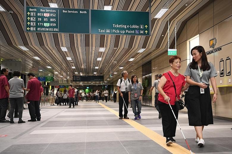 People with visual impairment being guided by SMRT staff yesterday in a tour of the Yishun Integrated Transport Hub, which will open next month. The hub is also a place where the public can take commuters with dementia; trained staff will then attend