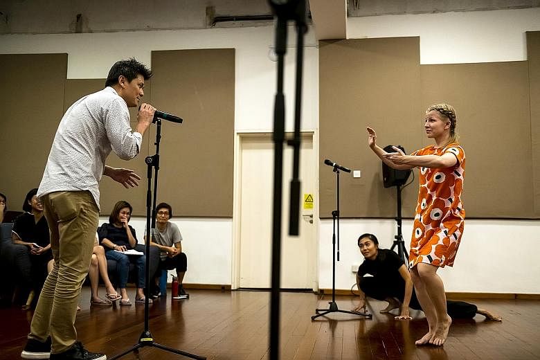 Ang Xiao Ting (in black, on floor) and Sini Rautjoki (in orange) react to an audience member speaking into the microphone in Ming Poon's The Pledge at Project Utopia.