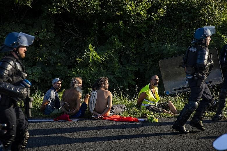 From left: Anti-G-7 activists being detained by French national police near Hendaye, France, on Friday; demonstrators carrying rubber boats, in a reference to migrants crossing the Mediterranean, during a protest in Hendaye yesterday; and a protester