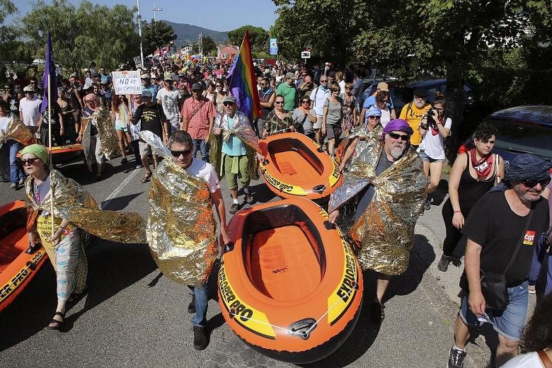 From left: Anti-G-7 activists being detained by French national police near Hendaye, France, on Friday; demonstrators carrying rubber boats, in a reference to migrants crossing the Mediterranean, during a protest in Hendaye yesterday; and a protester