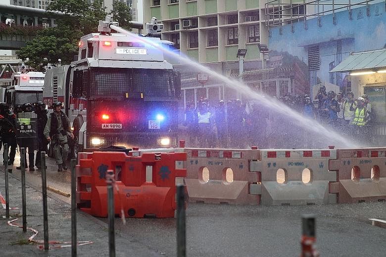 An anti-riot police vehicle equipped with a water cannon clearing the road of a barricade set up by protesters in Kwai Fong and Tsuen Wan, in Hong Kong. Traffic was paralysed after hundreds of black-clad protesters put up barricades made of dismantle