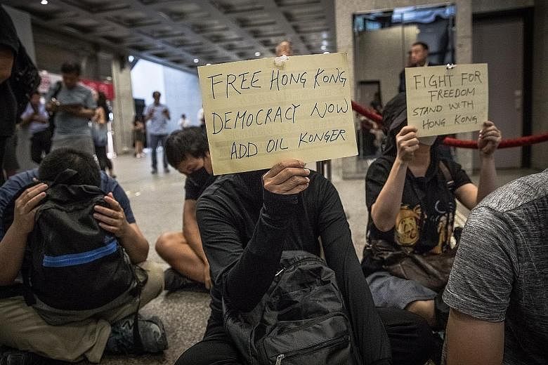 Protesters holding up posters during a sit-in assembly at the Revenue Tower in Wan Chai, Hong Kong, yesterday. PHOTO: EPA-EFE