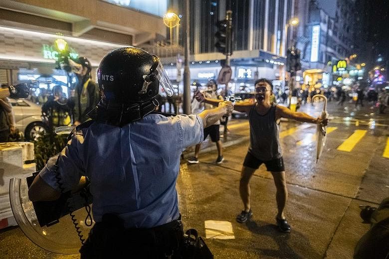A police officer drawing a pistol on a protester during a rally in Hong Kong on Sunday, amid escalating tensions in recent weeks.