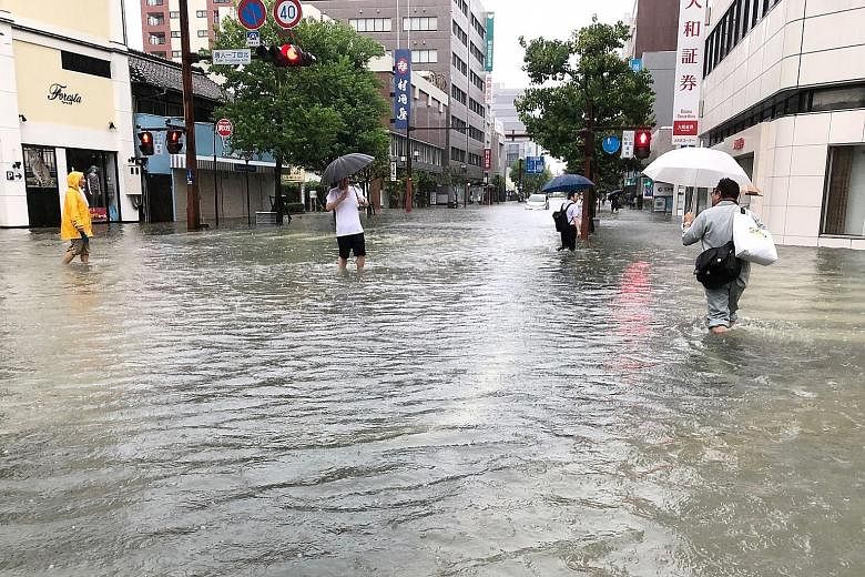 People wading through floodwaters in Saga city, Japan, yesterday. The authorities said they received multiple reports of houses flooded in Saga prefecture.