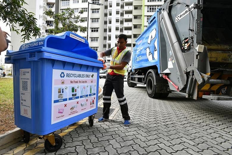 Recycling truck attendant Mohamat Hadilusandy Abdul Hadi, 26, with a bin bearing the new label, which prominently states that no food or liquids are allowed in the recycling bin. Achieving the target of reducing waste sent to the offshore Semakau Lan