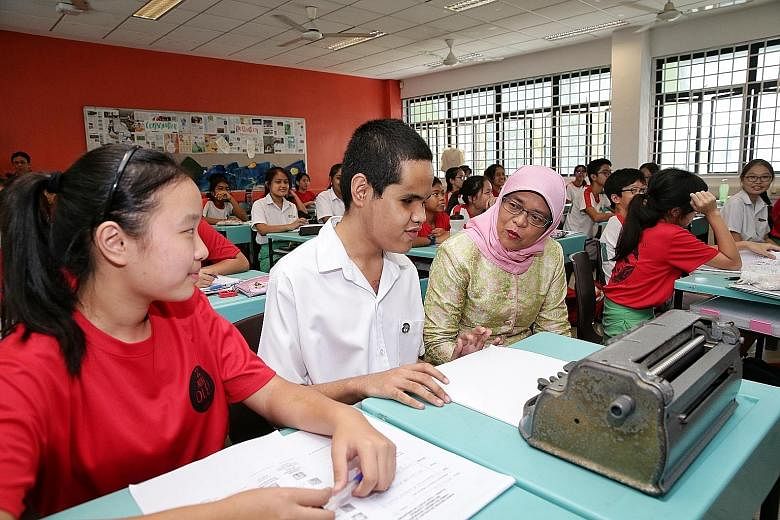 President Halimah Yacob interacting with visually impaired Secondary 2 student Lawrence Gabriel V. Angel, 15, in a geography class during her visit to Ahmad Ibrahim Secondary School yesterday. Next to Lawrence is Secondary 2 student Goh Si Ying, 14, 