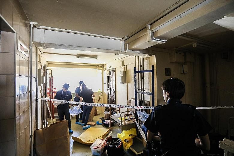 Police officers gathering evidence from inside the unit at Block 191 Lorong 4 Toa Payoh yesterday morning.