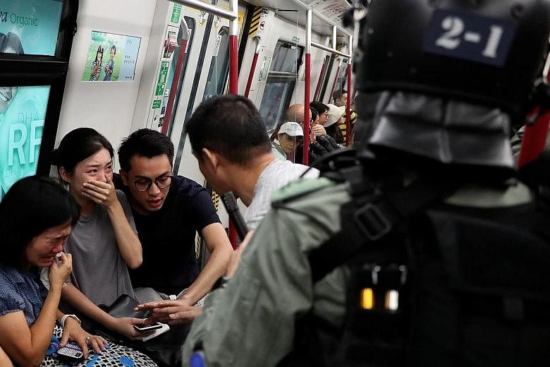 Commuters reacting as police officers looking for protesters raided a metro train in Hong Kong yesterday. The night before, officers had stormed a train carriage at Prince Edward MTR station, hitting people inside with batons and using pepper spray. 
