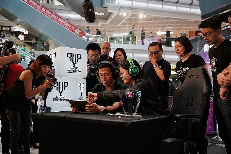 Education Minister Ong Ye Kung trying his hand at popular e-sports game Mobile Legends at Singtel's inaugural PVP Inter-Campus League at Funan mall yesterday. 