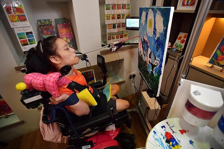Ms Elaine Eng, who loves to paint, using the E-Canvas device that works by voice command. The 19-year-old, who has spastic-dystonic quadriplegia and is unable to use her arms, legs and body, paints by wielding a brush in her mouth. ST PHOTO: LIM YAOH