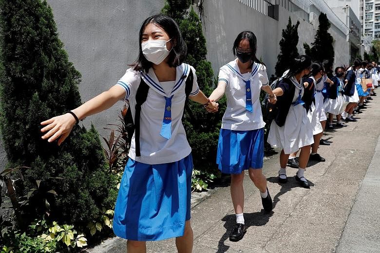 Secondary school students in Hong Kong joining hands to form a human chain as they boycotted classes for a second day and joined pro-democracy rallies. PHOTO: REUTERS People participating in a protest rally at Tamar Park in front of government buildi