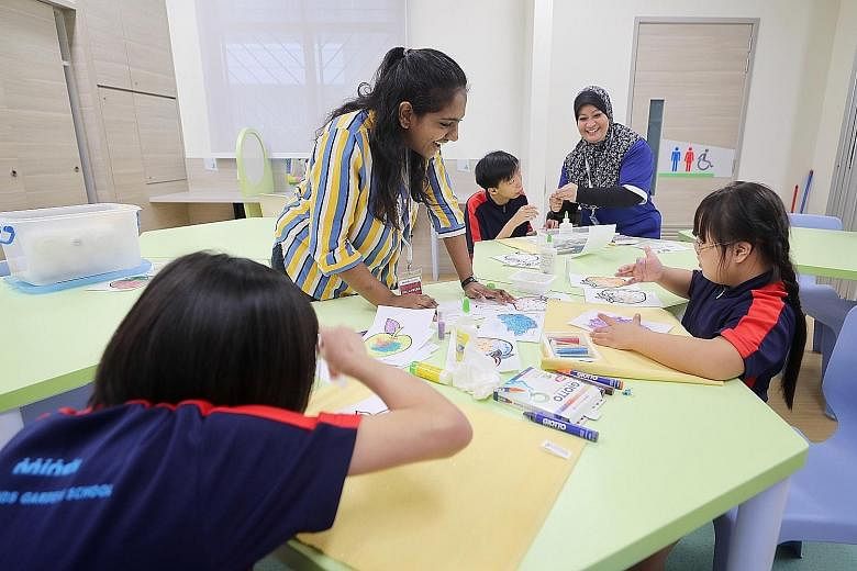 Above: Volunteer Nagakalishwari Ramesh (in stripes) and training officer Nurimah Ghani helping Minds students (from left) Vicky Chew (back to camera), 12, Roy Hong, 17, and Amanda Wang, nine, with their glitter art at Minds Raintree yesterday. Below: