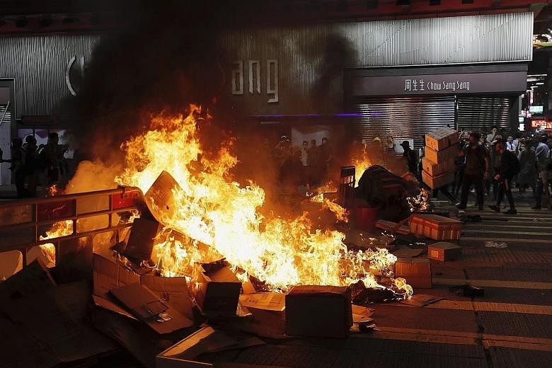 Protesters standing next to a burning barricade they set up during a protest in Mong Kok last night. Police fired tear gas and rubber bullets to disperse the crowd. PHOTO: ASSOCIATED PRESS