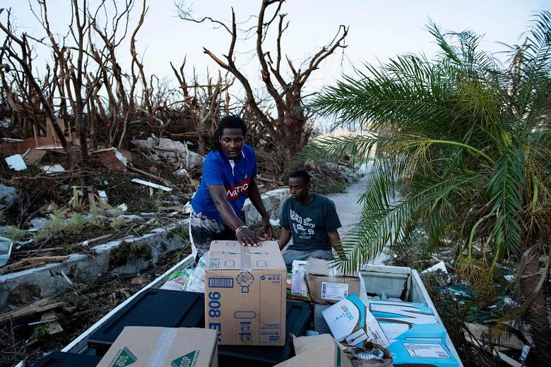 Above: Volunteers with World Central Kitchen transporting food supplies for survivors of Hurricane Dorian on Thursday in Marsh Harbour, Great Abaco, the Bahamas. Below: Residents of a caravan park in Emerald Isle, North Carolina, surveying the damage