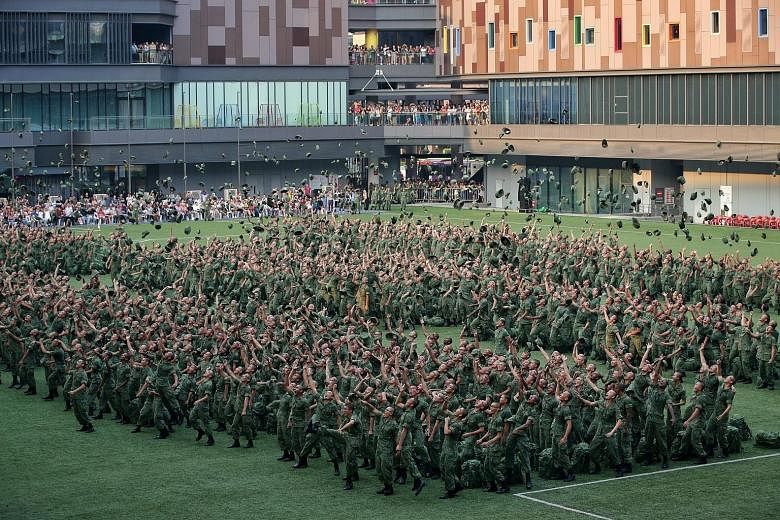 Recruits tossing their jockey caps in the air at Our Tampines Hub yesterday, to celebrate their graduation from basic military training. The site was chosen as it was big enough and easily accessible to the families of the graduating recruits, said C