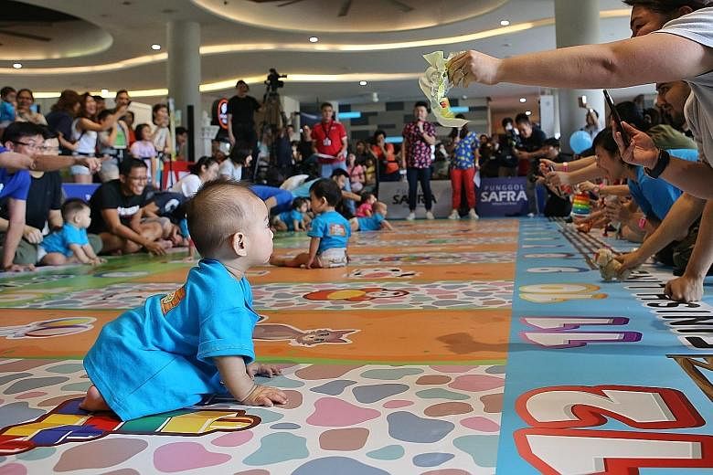 Parents cheering their babies on as they took part in a "diaper dash" competition yesterday at the My Family Fiesta event at Safra Punggol. PHOTO: LIANHE ZAOBAO